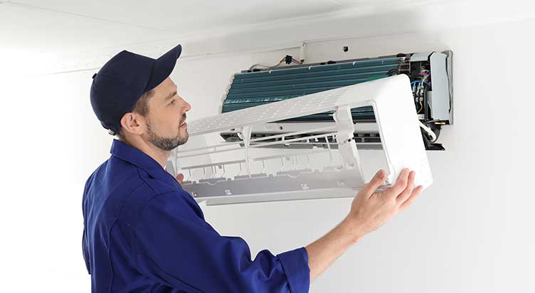 Technician inspecting wall-mounted AC unit's interior