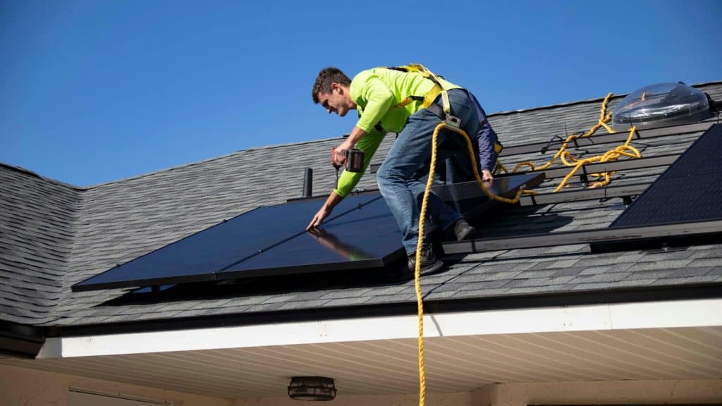 solar panel technician installing solar on a roof