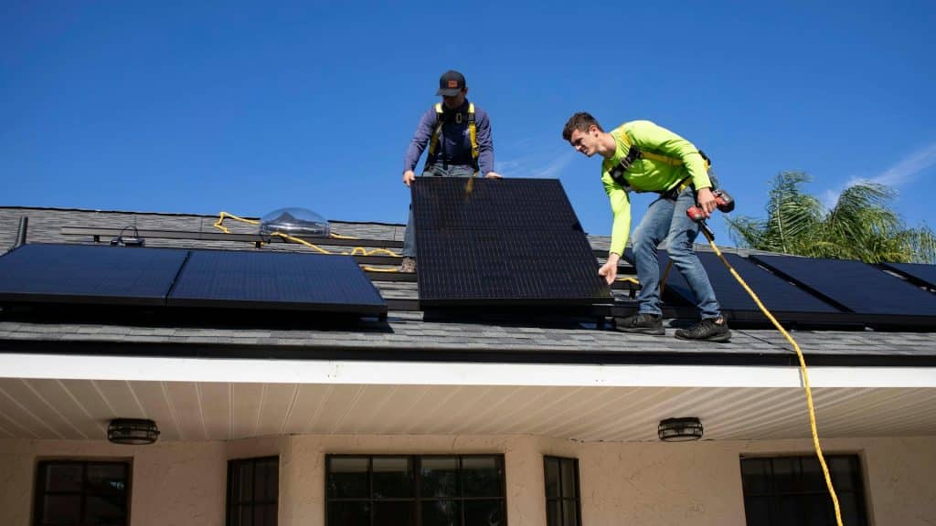 two solar installation technicians on a roof installing solar panels